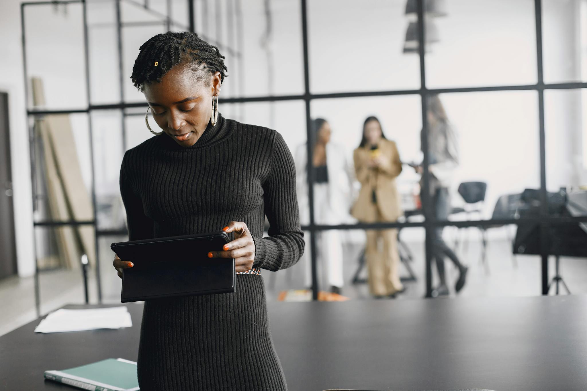 Focused African American woman using a tablet in a modern office setting.